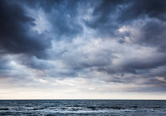 Dramatic stormy dark cloudy sky over sea, natural photo background